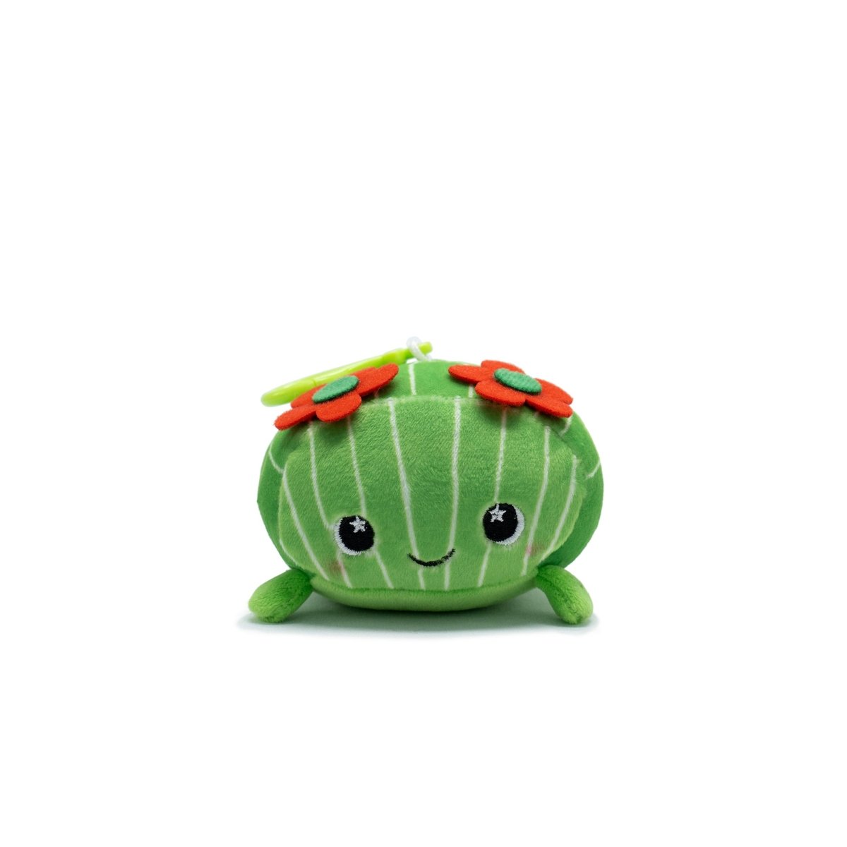 The Maya the Cactus Plush Clip-On is a charming mini plushie shaped like a green cactus with white vertical stripes. It features an adorable face with embroidered eyes and a small smile, topped with two bright red and orange flowers on a white background.