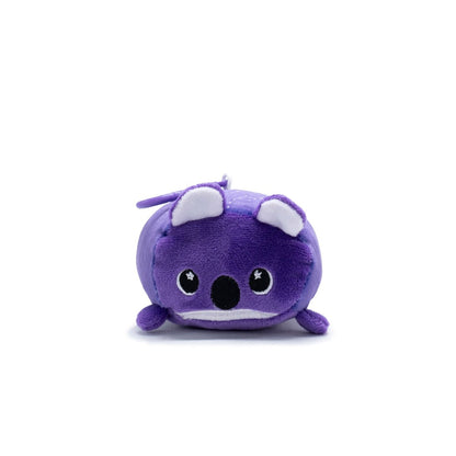 Taz the Koala Plush Clip-On from Moosh-Moosh Series 5 is a compact, portable toy resembling a cartoonish purple animal with white ears and large starry eyes. It lies on a flat surface against a white background.