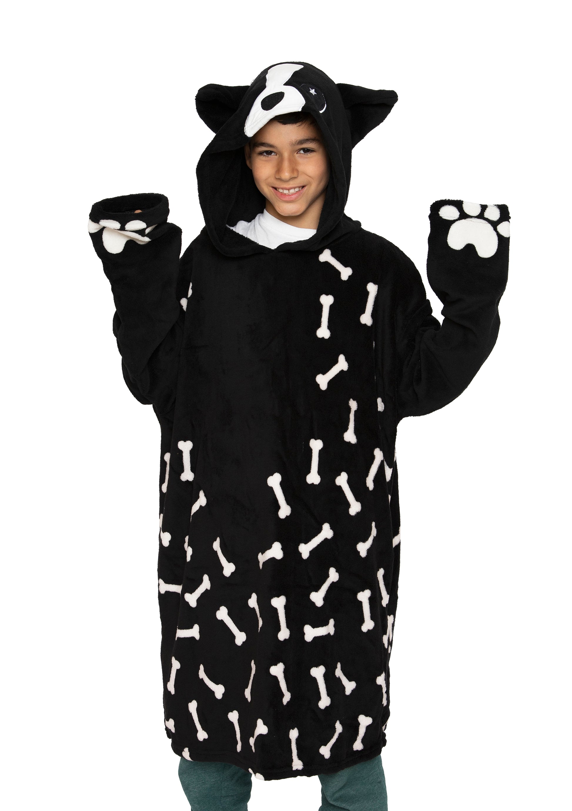 A smiling child wears the Hooded Blanket - Ollie the Corgi, a cozy black hooded costume featuring a cartoon dog face, cute dog ears, paw mittens with white paw prints, and playful bone patterns.
