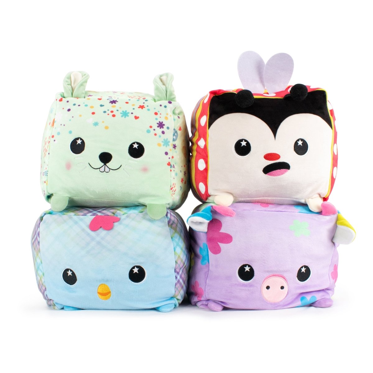 Stacked in two rows are four Plush Pals plush cube toys: Hoppy the Bunny Plushie in green with floral patterns and a ladybug with a red body on top, and a blue bird with plaid patterns alongside a pink pig on the bottom. All feature sensory softness and cute expressions.