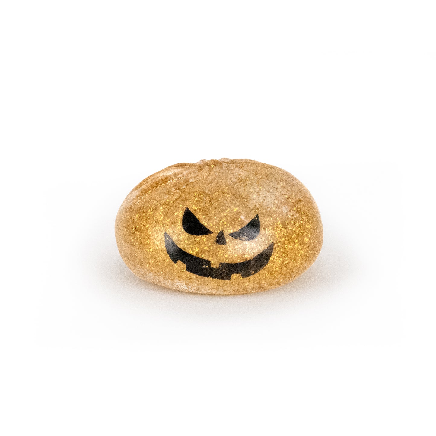 A small, round, gold glittery jelly toy called Bubblegum’s Favorite Toy - Spooky Mystery Dumpling, featuring a black jack-o’-lantern face design, sits on a white background.