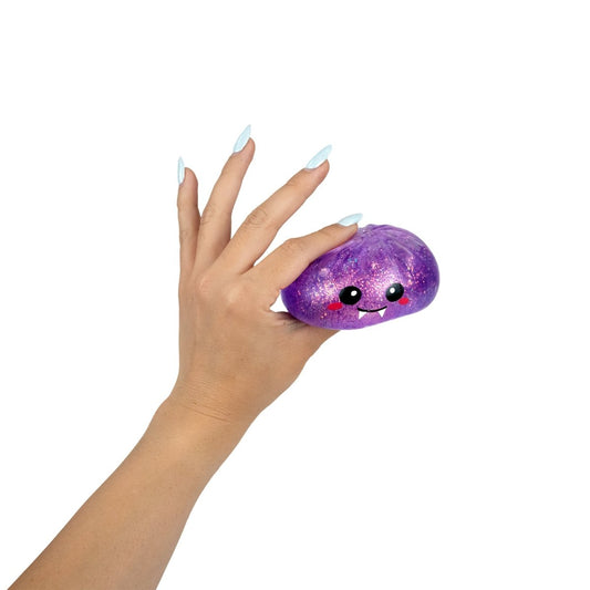 A hand with light blue nails squeezes Bubblegum’s Favorite Toy - Spooky Mystery Dumpling, a purple, glittery squishy toy featuring a cute, smiling face with pink cheeks, against a white background.