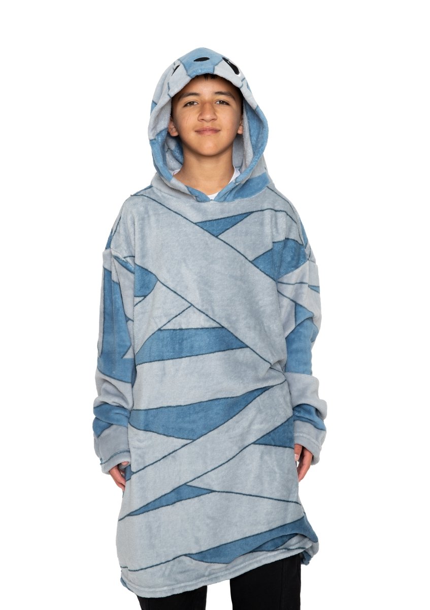 A young person smiles while wearing the Bed Klothes Nile the Mummy Hooded Blanket in blue and gray, standing against a plain white background.