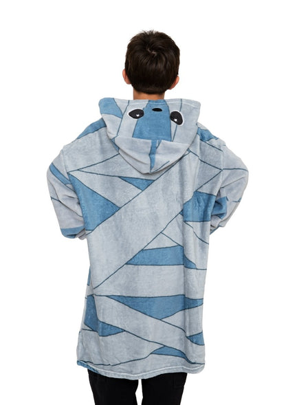 A person faces away, wearing the Nile the Mummy Hooded Blanket—a cozy blue kids fleece blanket with wide cartoon eyes and bandage patterns, perfect for Halloween.