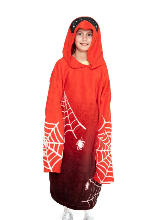 A child smiling and standing against a white background, wearing the Muffet the Spider Hooded Blanket featuring spiderweb and spider designs.