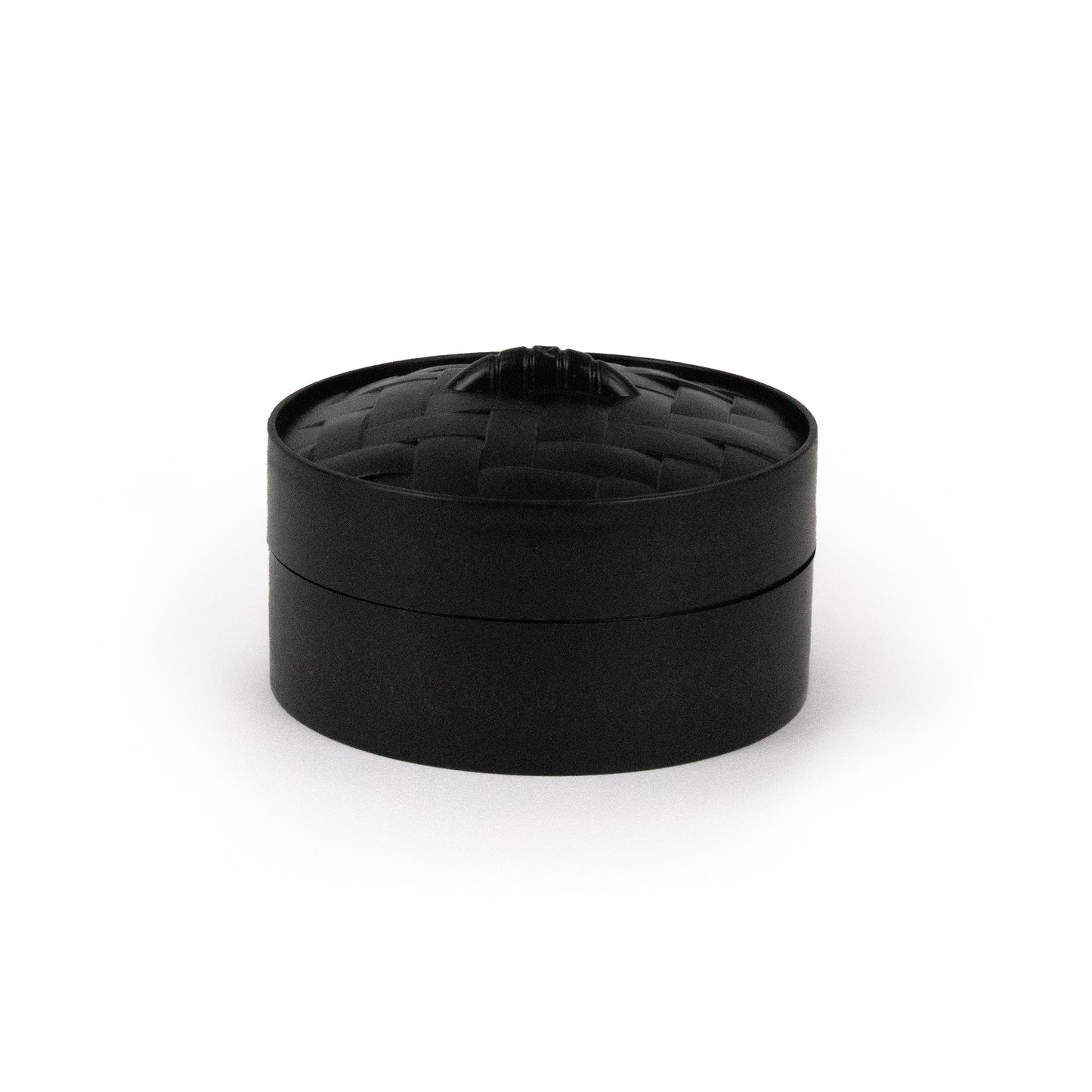A small, round, black container labeled “Bubblegum’s Favorite Toy - Spooky Mystery Dumpling” features a woven-texture lid with a subtle knob on top, displayed against a plain white background.