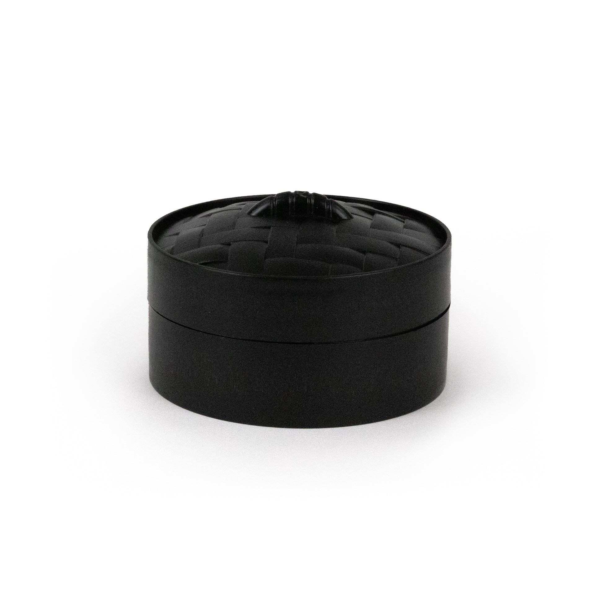 A small, round, black container labeled “Bubblegum’s Favorite Toy - Spooky Mystery Dumpling” features a woven-texture lid with a subtle knob on top, displayed against a plain white background.