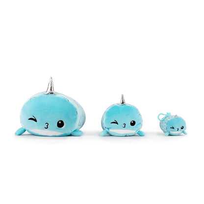 Three cuddly Hershel the Narwhal plush toys in three sizes, each with a silver horn: the largest on the left, medium in the middle, and smallest on the right. Each toy has winking eyes and little smiles.