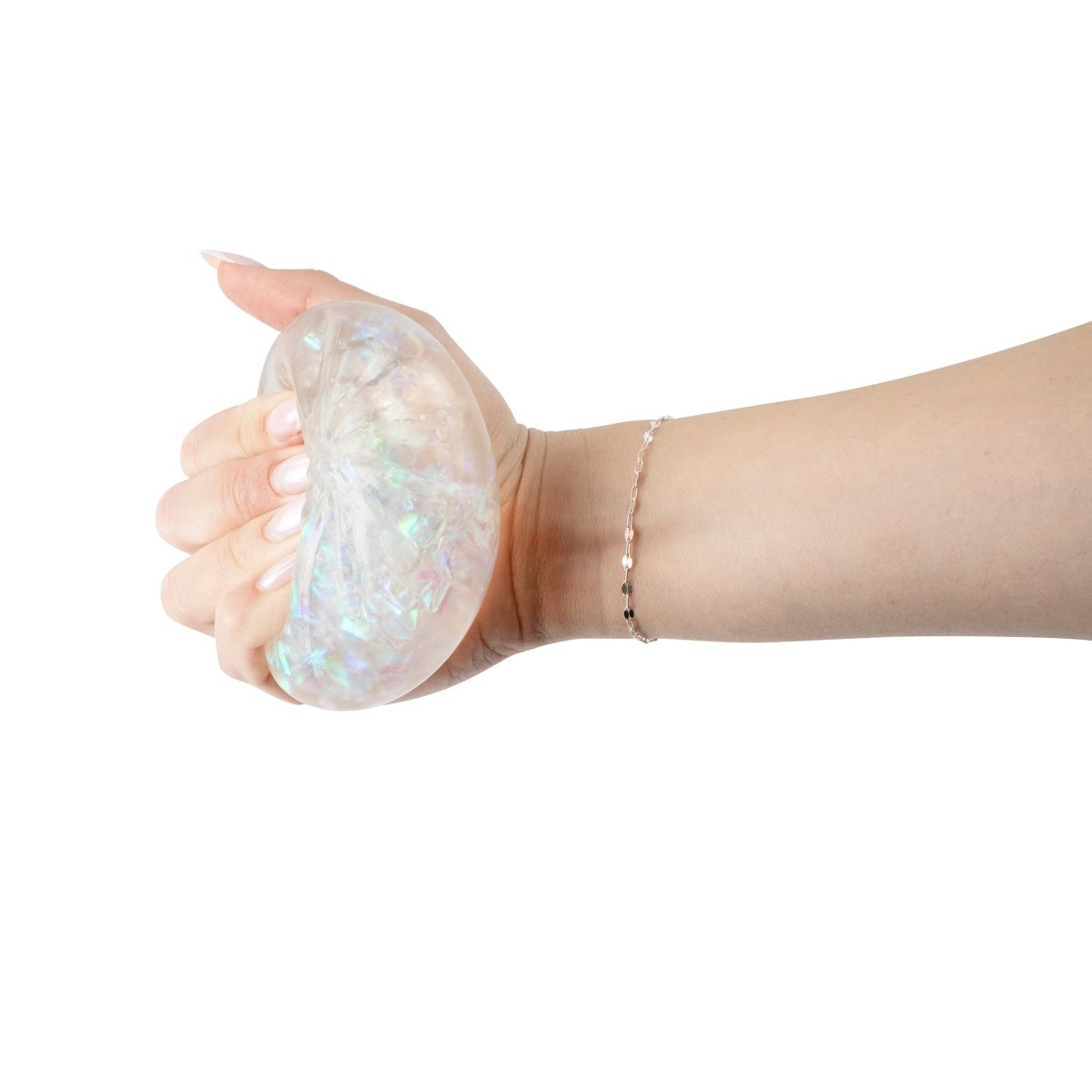 A hand squeezes Bubblegum's Favorite Toy - Mystery Dumpling, a translucent, iridescent stress relief squishy, against a white background. The toy glimmers as the person wearing a delicate bracelet gently presses it.
