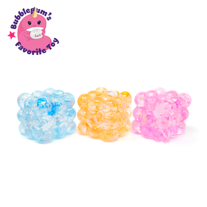 Three translucent Glitter Bubble Cubes in blue, yellow, and pink sit on a white background. In the top left corner, a pink cartoon mascot appears alongside the text “Bubblegum’s Favorite Toy – Glitter Bubble Cube.”.