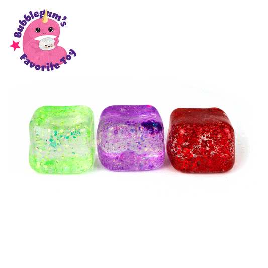 Three glittery, translucent Glitter Sugah-mals Cubes v.2 in green, purple, and red from Bubblegum's Favorite Toy are lined up on a white background, with a pink cartoon character and the text "Bubblegum's Favorite Sensory Toy" in the top left corner.