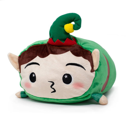 Jingle the Elf Plushie is a festive holiday plush shaped like an elf, featuring pointed ears, rosy cheeks, brown hair, a green hat with a yellow pom-pom, and a green outfit. It lies on its belly with a surprised expression.