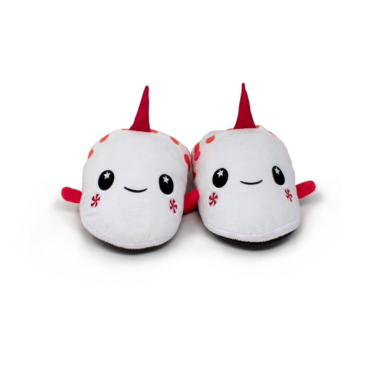 A pair of Mintie the Mint Slippers—plush white holiday slippers shaped like adorable narwhals with red horns, smiling faces, and starry black eyes—set against a plain white background.