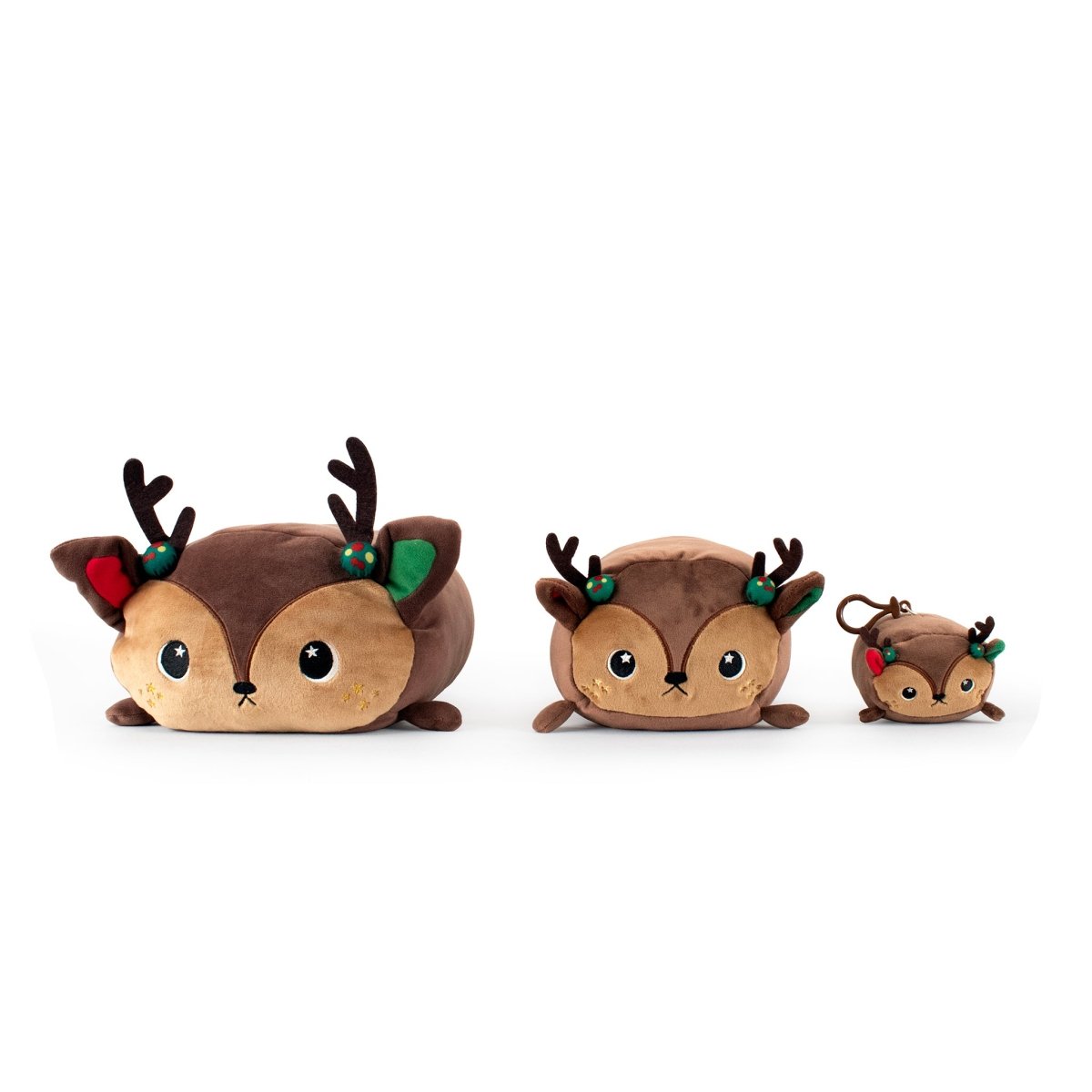 Three Mitzy the Reindeer Plushies—charming Christmas plush toys in various sizes—stand together, each showing off soft brown fur, big eyes, cute antlers, and holiday decorations on their festive ears.