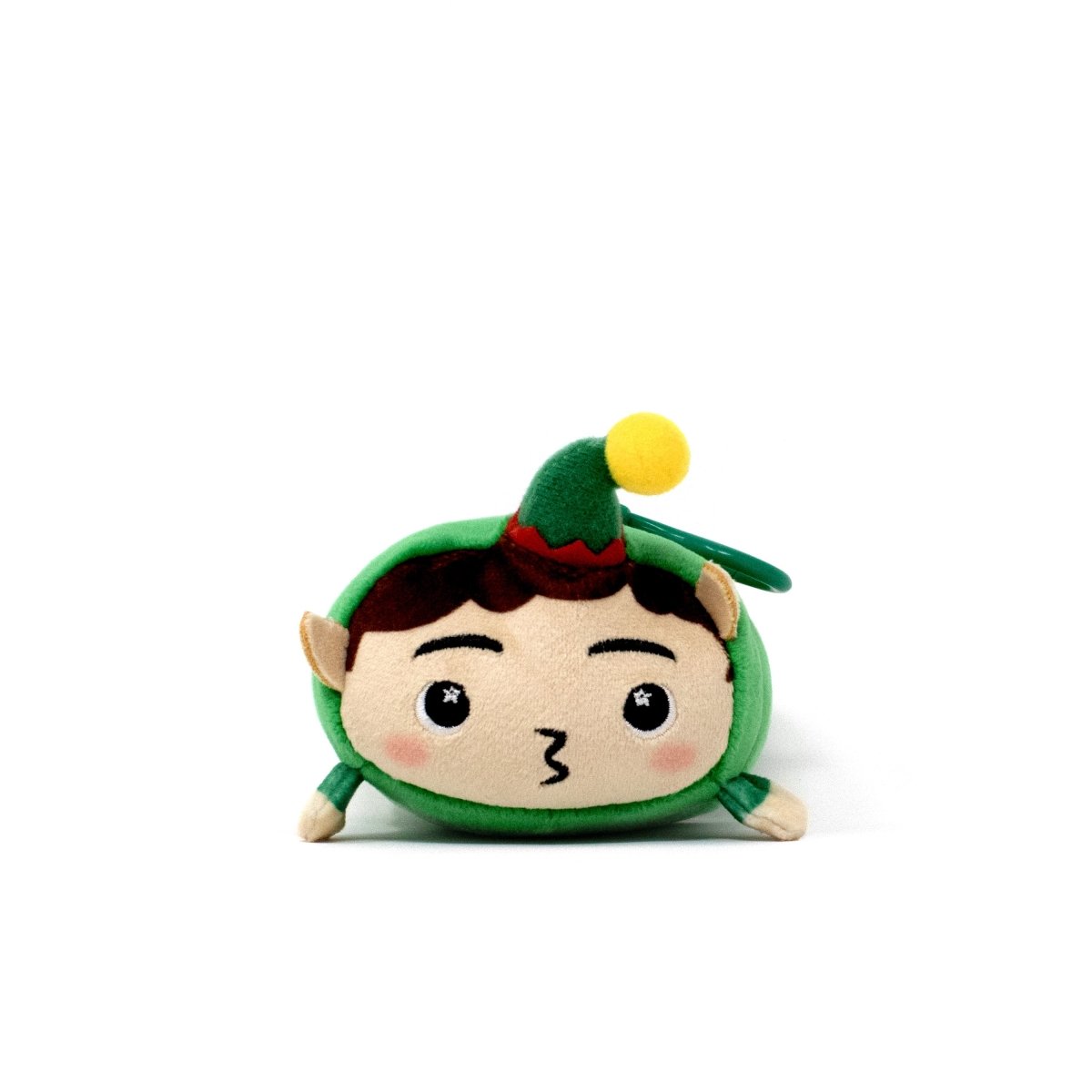 Jingle the Elf Clip-On is a small, round holiday plushie with a green hat, yellow pom-pom, pointy ears, and a puckered mouth, shown sitting on a white background.