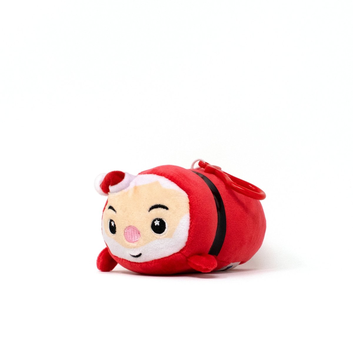 The Santa Clip-On is a small, round Christmas plushie resembling Santa Claus, featuring a red outfit, white trim, pink nose, and smiling face. It’s shown lying on its side against a white background.