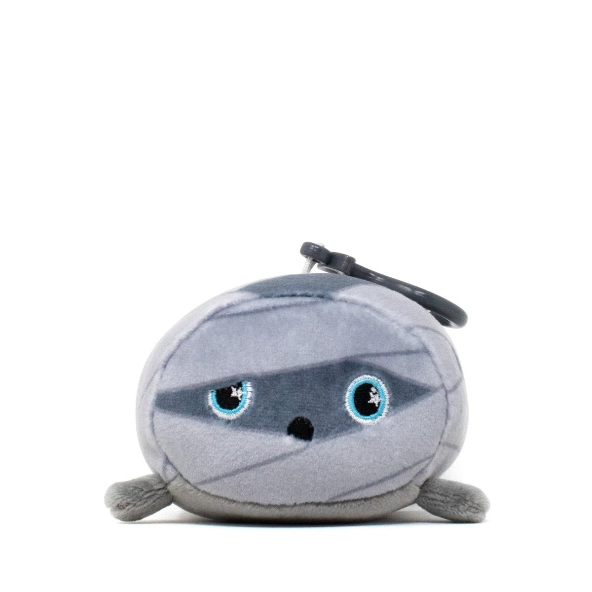Nile the Mummy Clip-On is a round, gray plush toy with blue eyes and a keychain attachment. This soft and cute stuffed animal boasts a friendly expression and a simple, cartoonish design that adds charm to any collection.