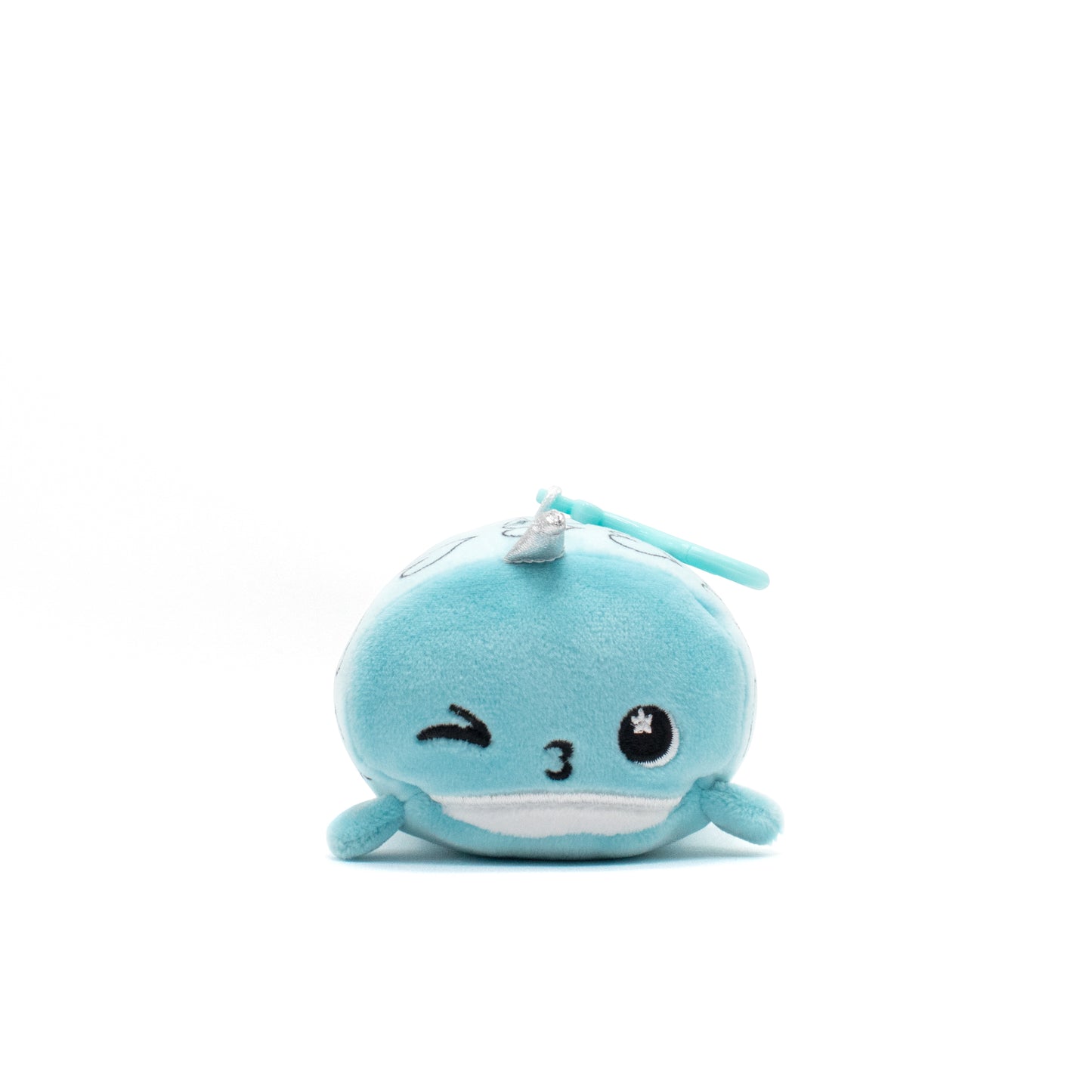 This adorable plush clip-on features Hershel the Narwhal, a soft, round blue stuffed animal with embroidered facial details like a winking eye and a smiling mouth on a white background.