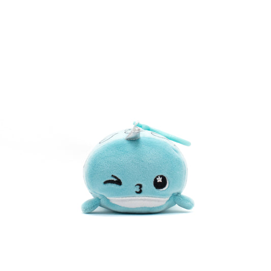 This adorable plush clip-on features Hershel the Narwhal, a soft, round blue stuffed animal with embroidered facial details like a winking eye and a smiling mouth on a white background.