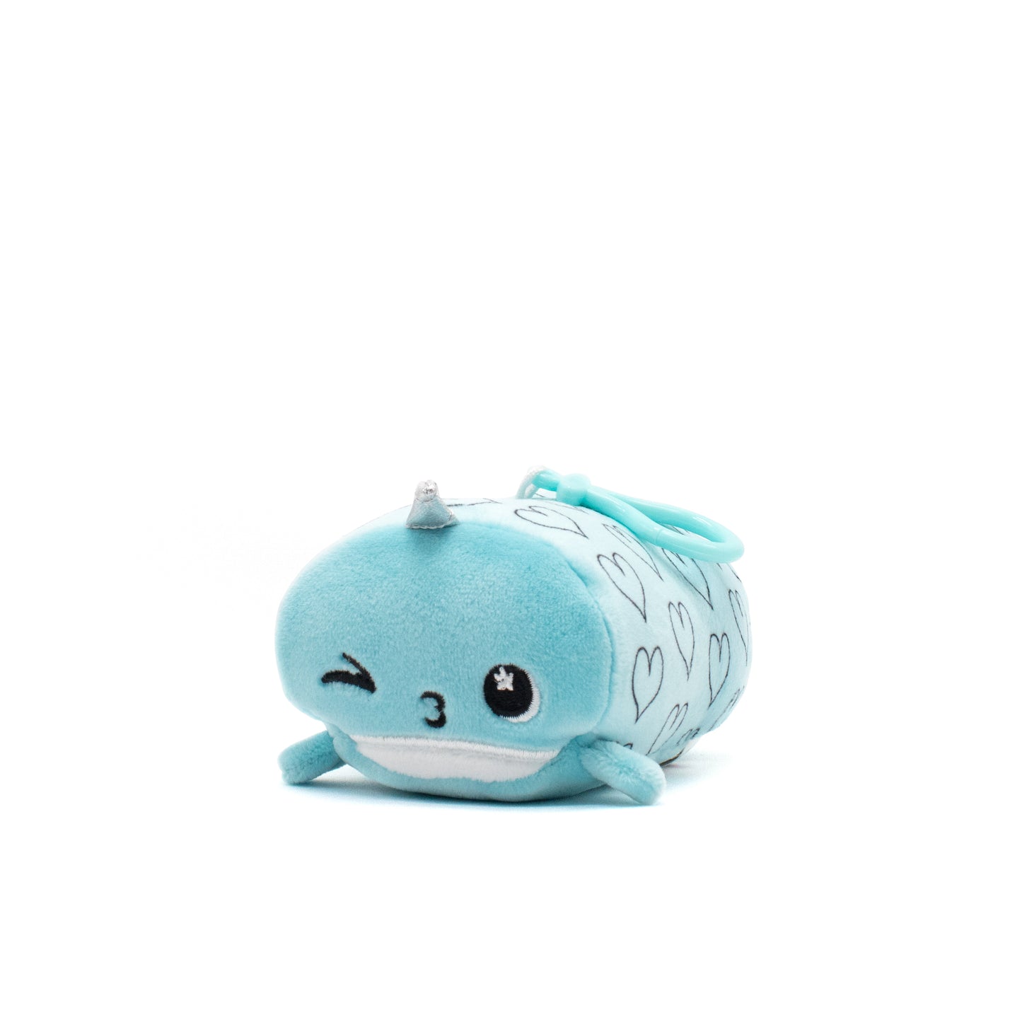 Hershel the Narwhal Plush Clip-On is a cute, soft blue toy with embroidered eyes—one winking—and a small horn. It features heart patterns on its back and includes a clip, all against a plain white background.