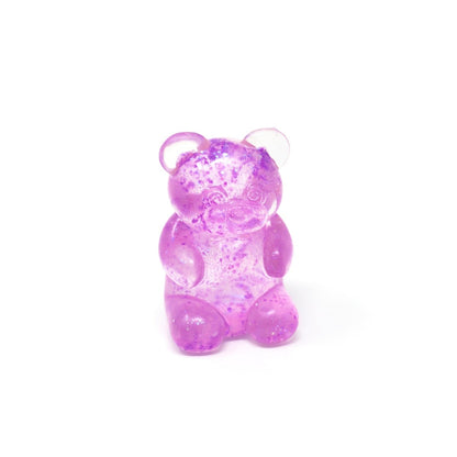 A translucent purple Glitter Maltose Bear from Bubblegum’s Favorite Toy, featuring small darker purple specks, sits upright on a white background—making it the perfect squishy stress relief sensory toy.