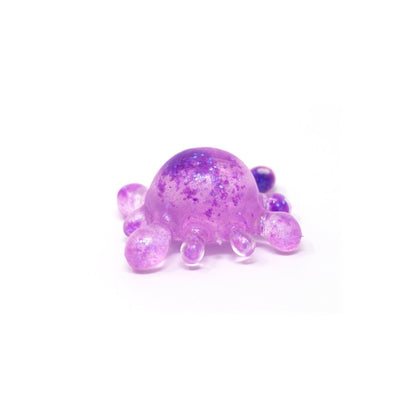 A small, dome-shaped, translucent purple Bubblegum’s Favorite Toy - Splat Squishy with glitter and six rounded protrusions sits on a white background, making it an adorable sensory toy perfect for stress relief squishy fun.