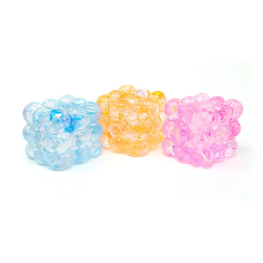 Three translucent Glitter Bubble Cubes from Bubblegum’s Favorite Toy, in blue, yellow, and pink, are arranged side by side on a white background.
