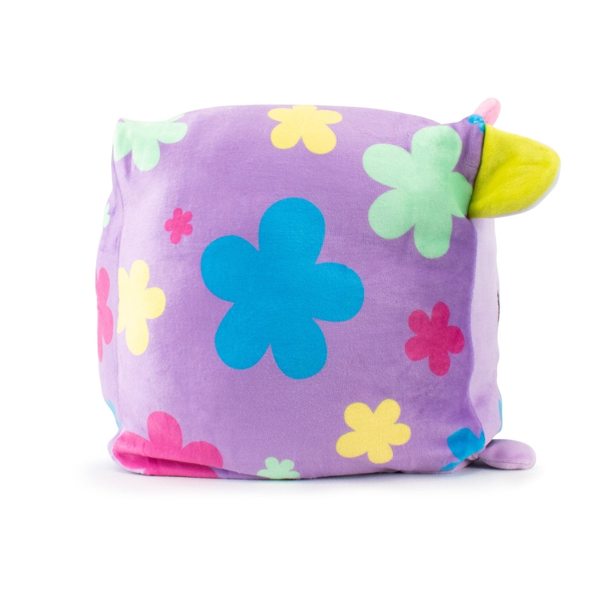 Pasquale the Cow Plushie is a plush, square-shaped pillow with a purple base, featuring colorful Easter plushie patterns in blue, pink, green, and yellow. It has a small yellow ear and pink tail resembling a cute cartoon animal. Enjoy its sensory softness and easy machine washability.