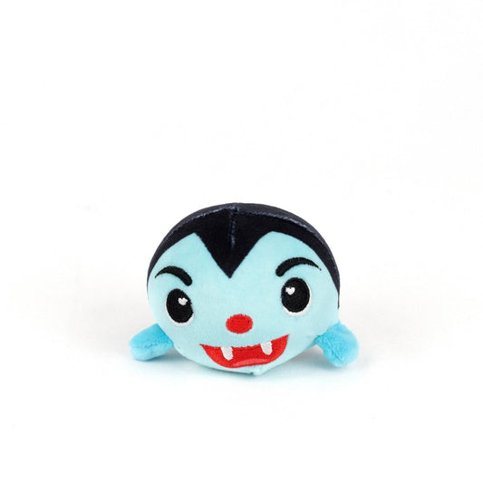 The Vlad Spooky Plushy Skwishy is a small, round plush toy with a blue face, black hair, red nose, fangs, tiny blue arms, and a cheerful expression—resembling a cute cartoon vampire.