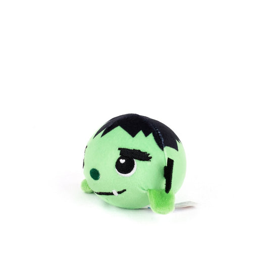 Frankie Spooky Plushy Skwishy is a small, round, green plush toy with black hair, white fangs, stitched eyebrows, and arms, resembling a cute cartoon monster. It sits on a white background.