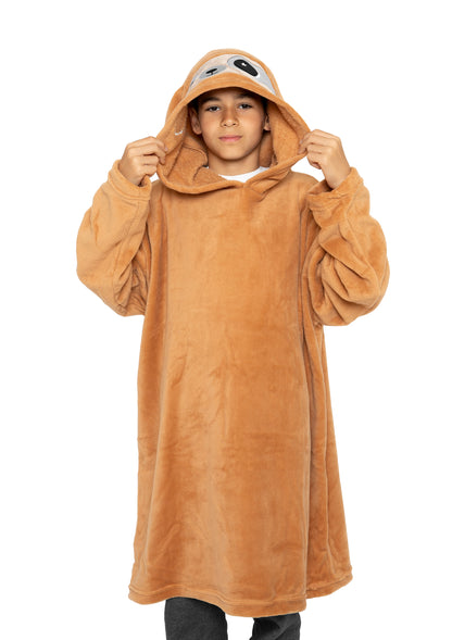 A young person wears a large, brown Hooded Blanket - Speedy the Sloth featuring a sloth face on the hood, stands against a white background, and holds the hood with both hands.