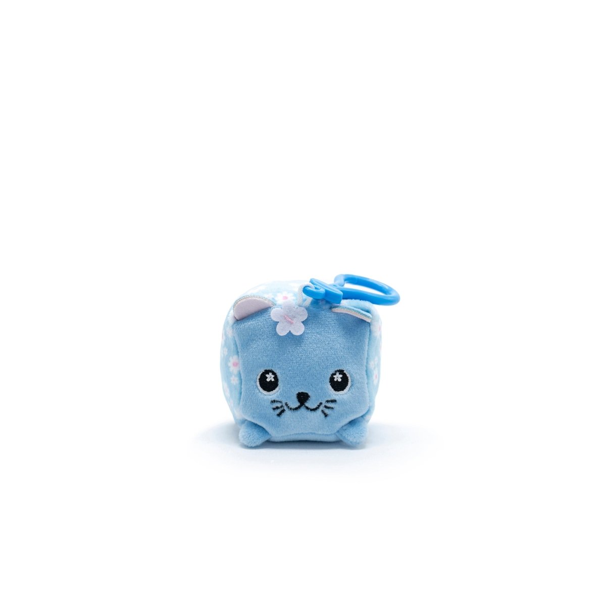 Product: Maisie the Cat Square Plush Clip-On. Cute blue plush cube with a cat face, part of Moosh-Moosh Series 1. Features embroidered eyes, whiskers, and a small flower on its head. Includes a blue loop for hanging against a white background.