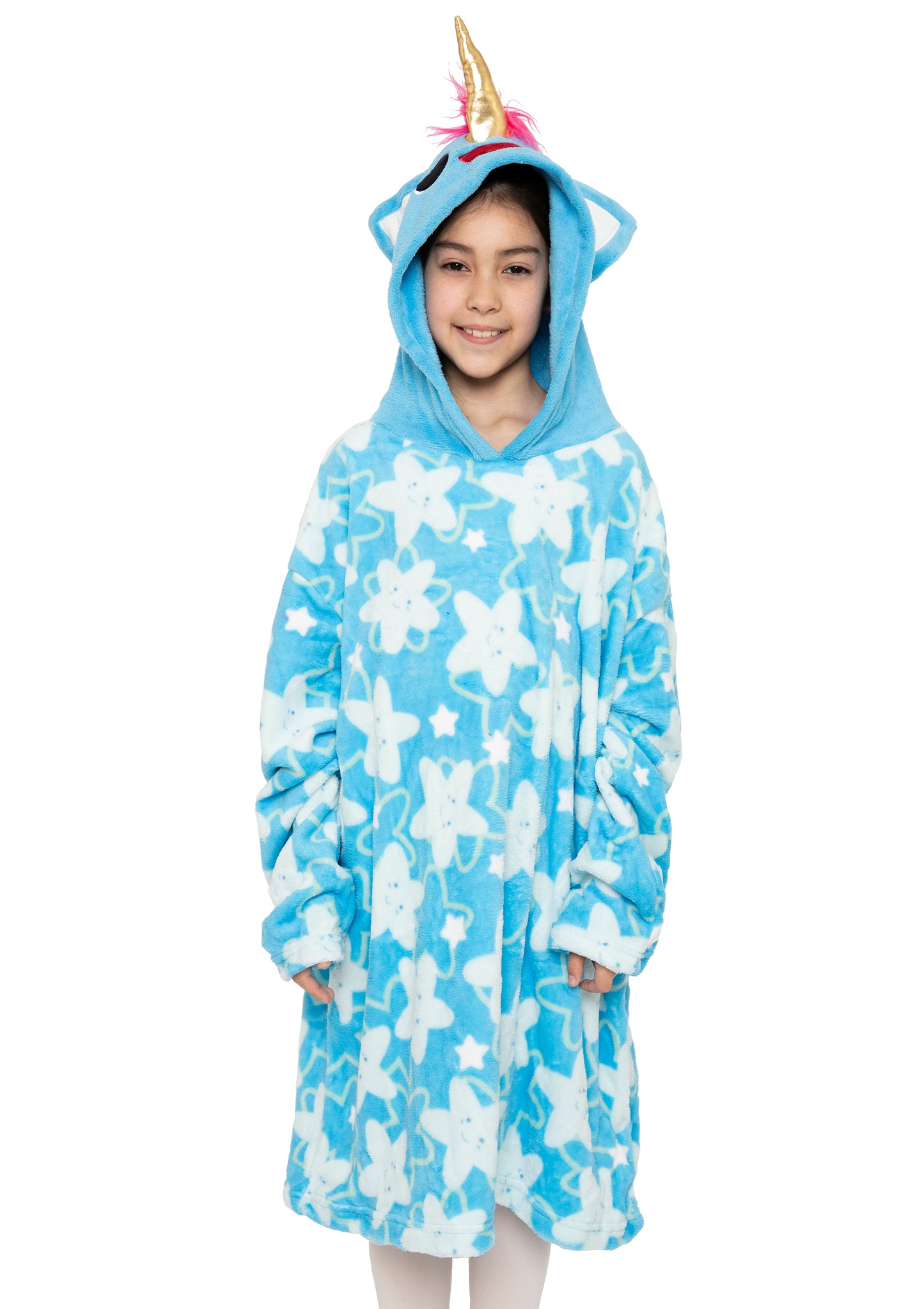 A child smiles wearing the Hooded Blanket - Sparkle the Unicorn, featuring a blue fabric with white stars, unicorn ears, a pink mane, and a gold horn on the hood, standing against a plain white background.
