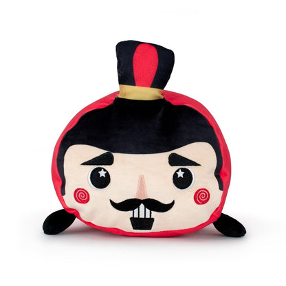 Voski the Nutcracker is a round, soft plush toy with a cartoon face, mustache, rosy cheeks, and a black top hat with red and yellow band. It features black arms, a red and black color scheme, and is machine washable.