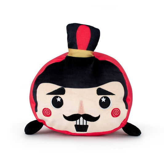 Voski the Nutcracker is a round, soft plush toy with a cartoon face, mustache, rosy cheeks, and a black top hat with red and yellow band. It features black arms, a red and black color scheme, and is machine washable.