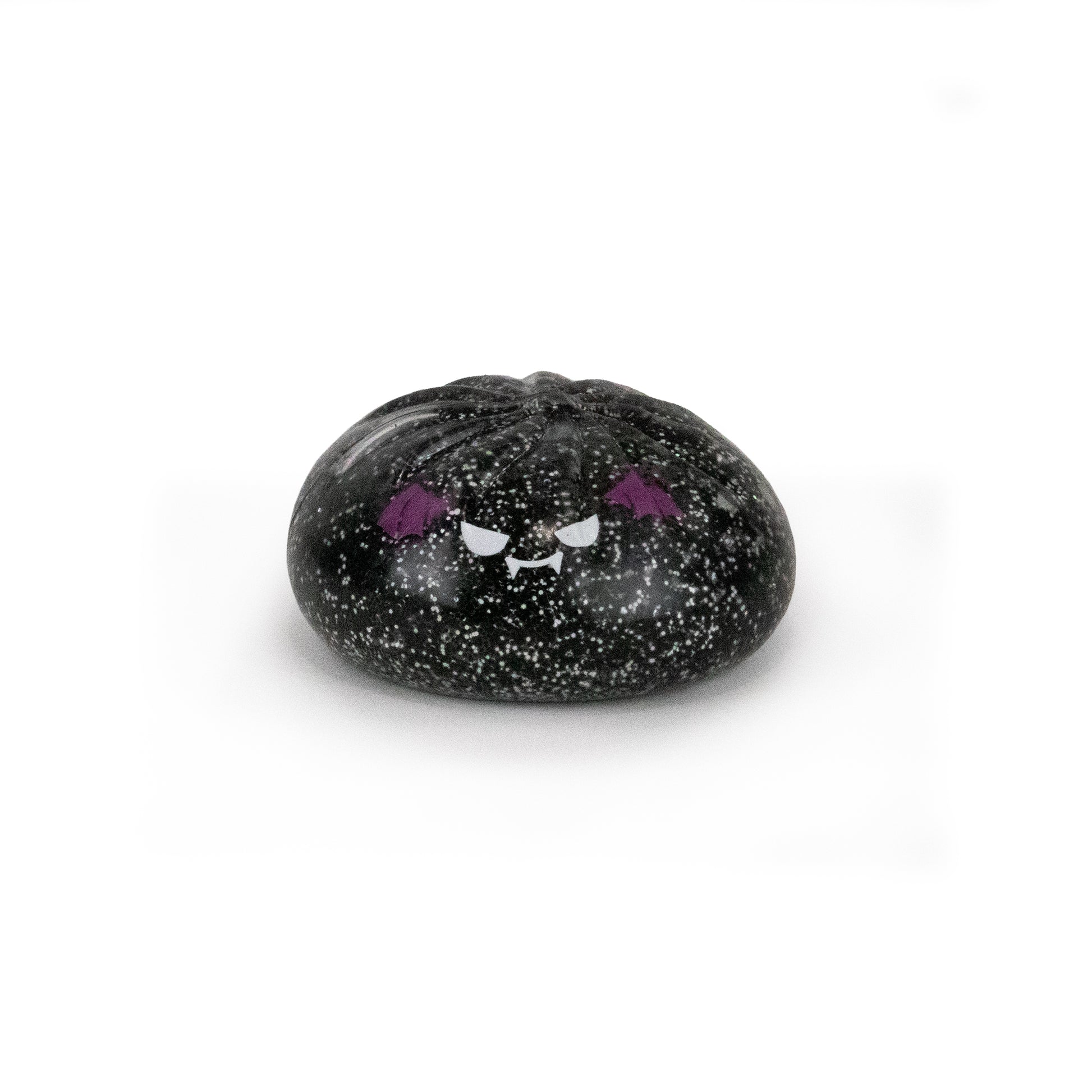 A small, round Spooky Mystery Dumpling from Bubblegum’s Favorite Toy collection, black with speckled details and an adorable angry cartoon face—complete with purple eyebrows and fangs—displayed against a plain white background.