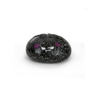 A small, round Spooky Mystery Dumpling from Bubblegum’s Favorite Toy collection, black with speckled details and an adorable angry cartoon face—complete with purple eyebrows and fangs—displayed against a plain white background.