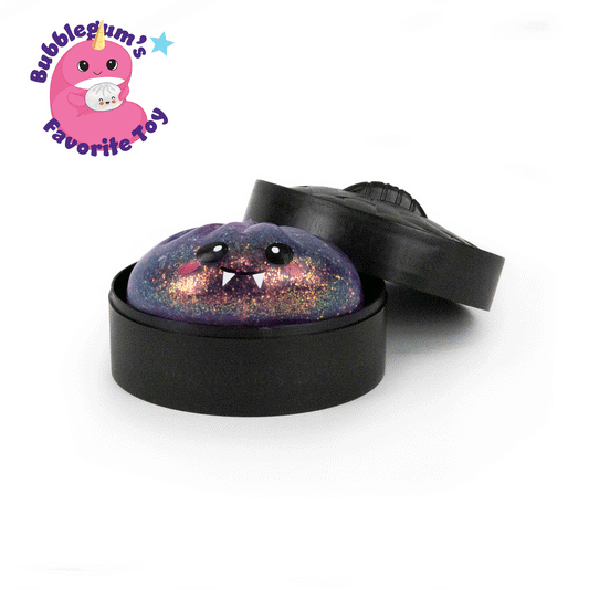 A round, glittery purple squishy toy with cartoon eyes and fangs sits in a black container with the lid partially off. This stress-relief collectible is called “Bubblegum’s Favorite Toy – Spooky Mystery Dumpling” and features a pink cartoon character in the top left corner.