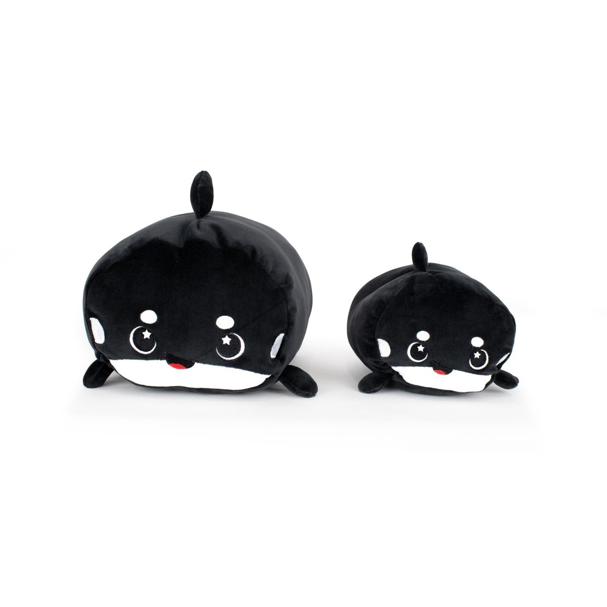 Fausto the Orca plushies—one large and one small—sit together on a white background, featuring black and white bodies, round shapes, smiling faces with rosy cheeks, and adorable star-shaped eyes.