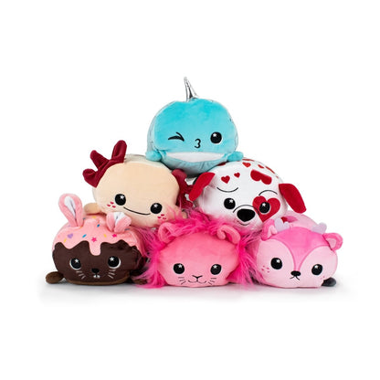 A group of cuddly plushies includes a blue narwhal, beige cat with a bow, Ed the Dalmatian with heart spots for Valentine's Day, a brown bunny sprinkled in color, a pink lion with a mane, and a pink fox. They are all ultra-soft and have big, round eyes.