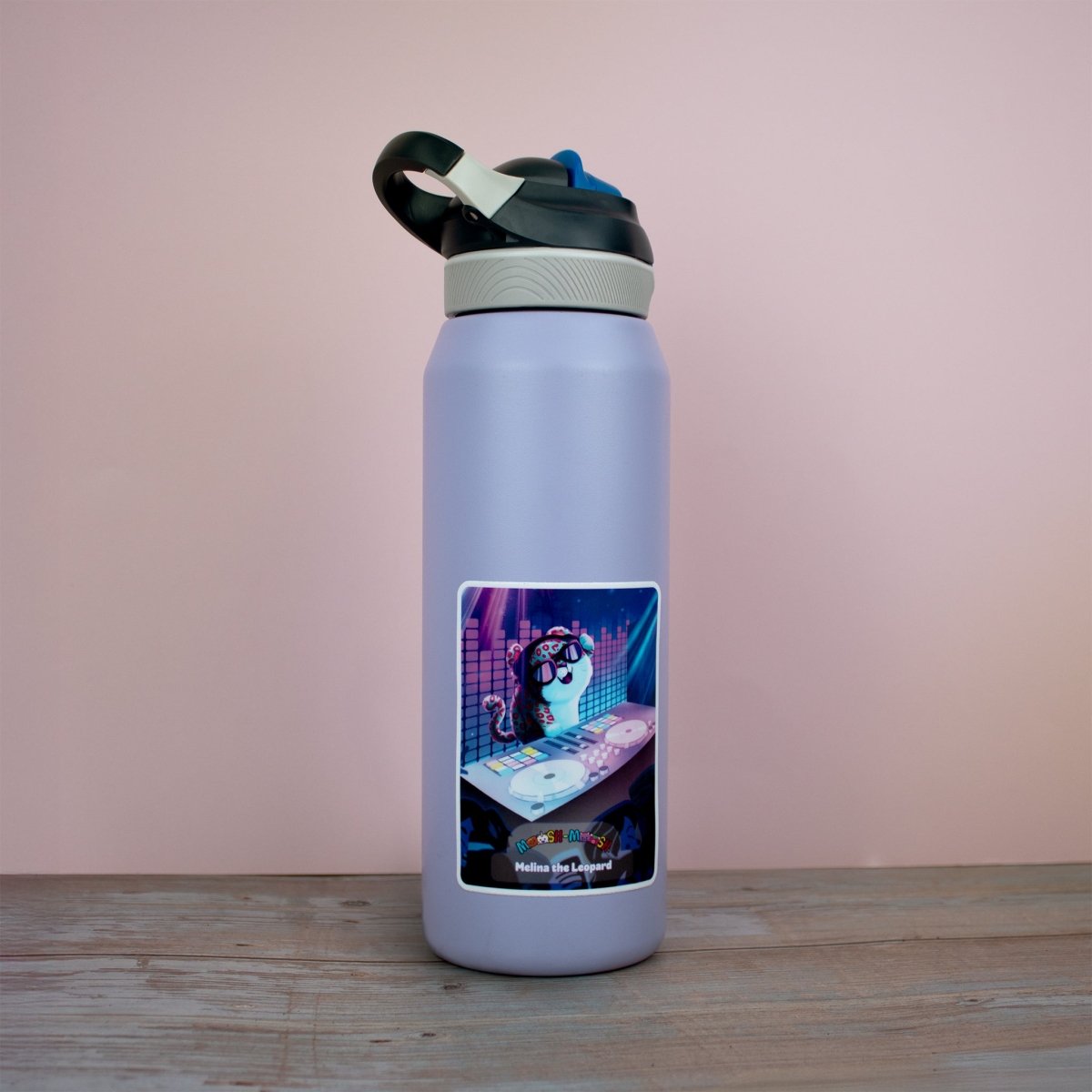 A pale lavender water bottle with a black and white lid sits on a wooden surface, decorated with a Moosh-Moosh 3" x 4" Vinyl Sticker of a cartoon cat DJ playing records amid colorful lights.