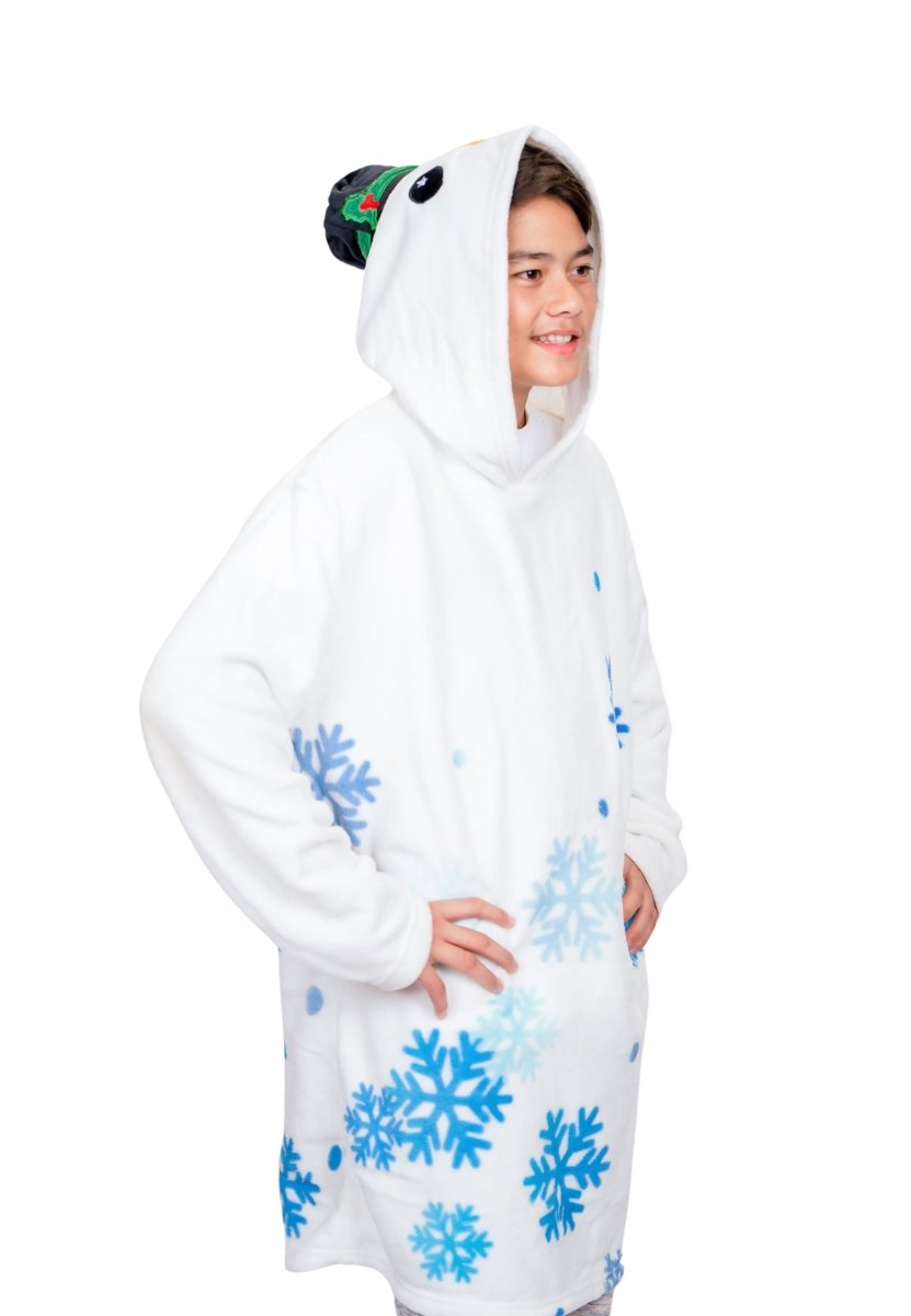 A person wearing the Jack the Snowman Hooded Blanket, featuring a cozy white design with blue snowflake patterns and a penguin headpiece, smiles and looks to the side like an adorable plushie on a plain white background.
