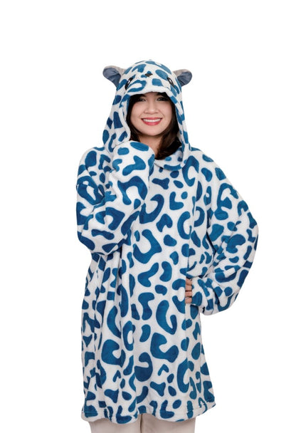 A person is smiling and wearing the Snowie the Leopard Hooded Blanket with bear ears on the hood, standing against a plain white background.