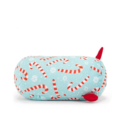 Mintie the Mint Narwhal Slumber is a light blue cylindrical Christmas plush pillow with red and white candy cane and snowflake patterns, two small red fins, and a red tail—perfect for festive decor or cuddling this holiday season!.