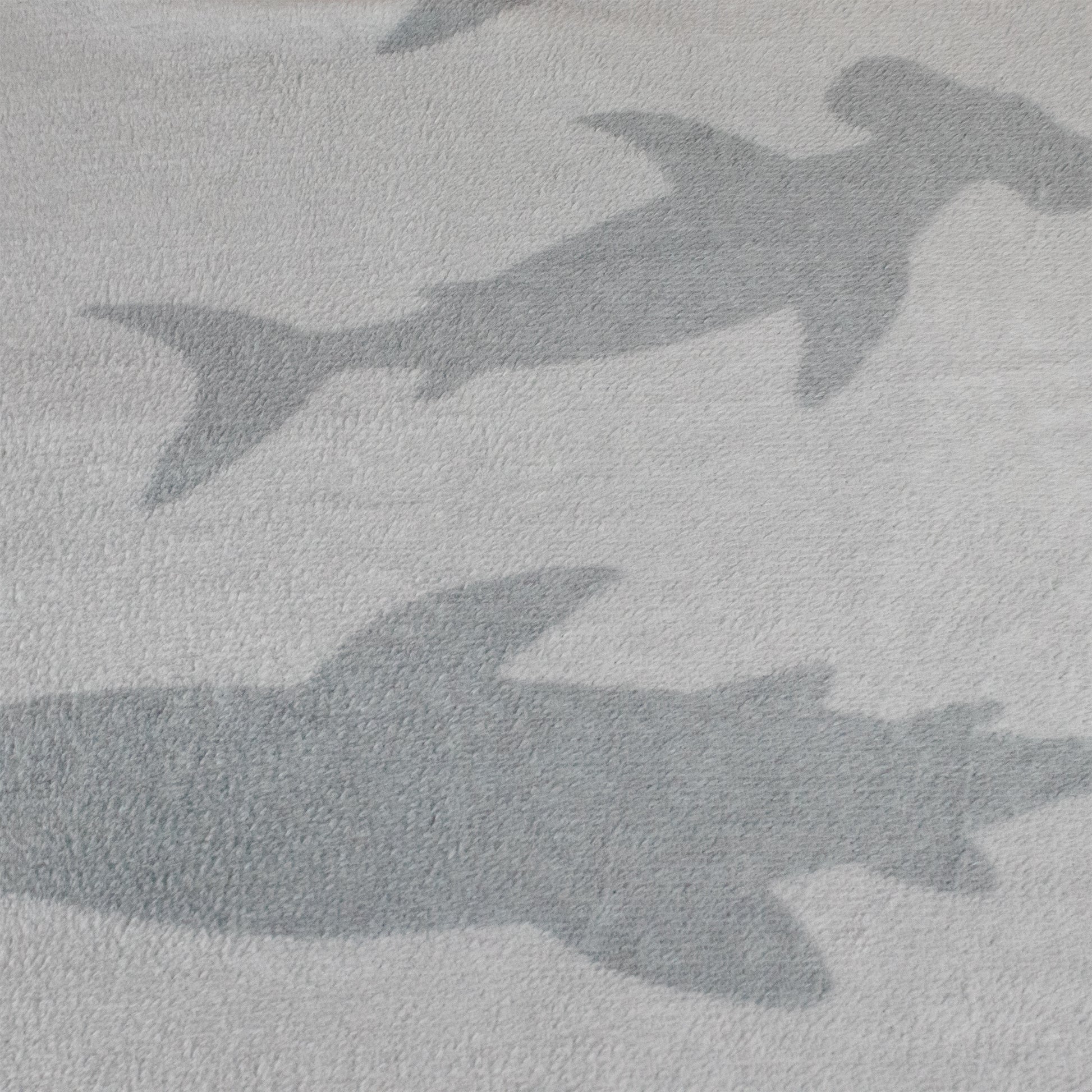 Two large shark silhouettes appear on a textured, light gray surface, resembling shadows or the 2-in-1 Pillow Blanket - Crush the Shark.