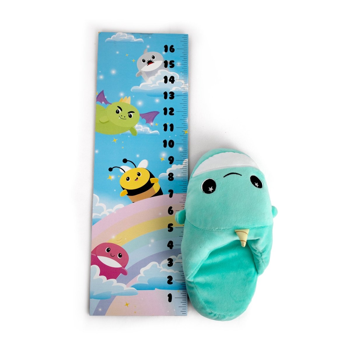 The Chunky Monkey Kids Slipper in plush aqua blue with a unicorn horn sits beside a vibrant height chart featuring cartoon clouds, stars, a purple dragon, yellow bee, white cloud, and rainbow on a white background.